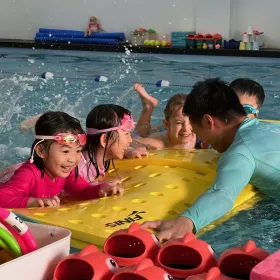 Children practising kicks on a float board with their coach