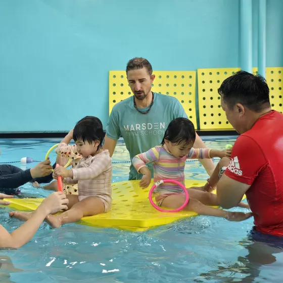 Coaches guiding young swimmers on a float mat